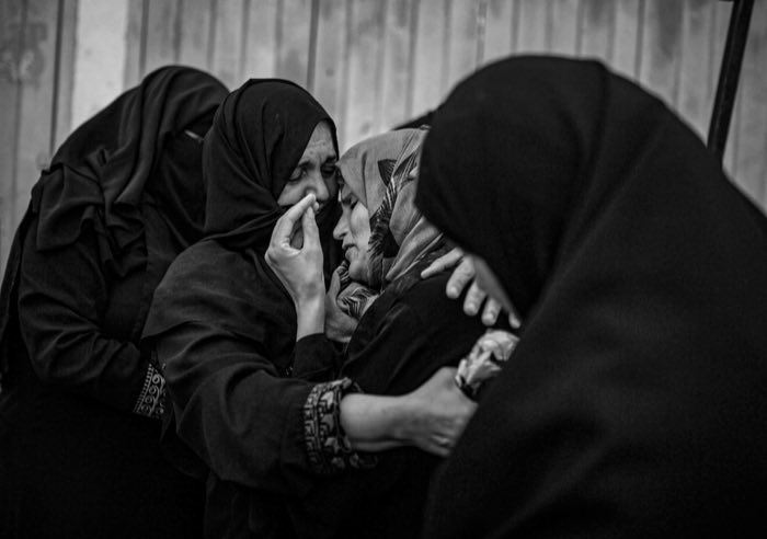 Women hold one another as they mourn.